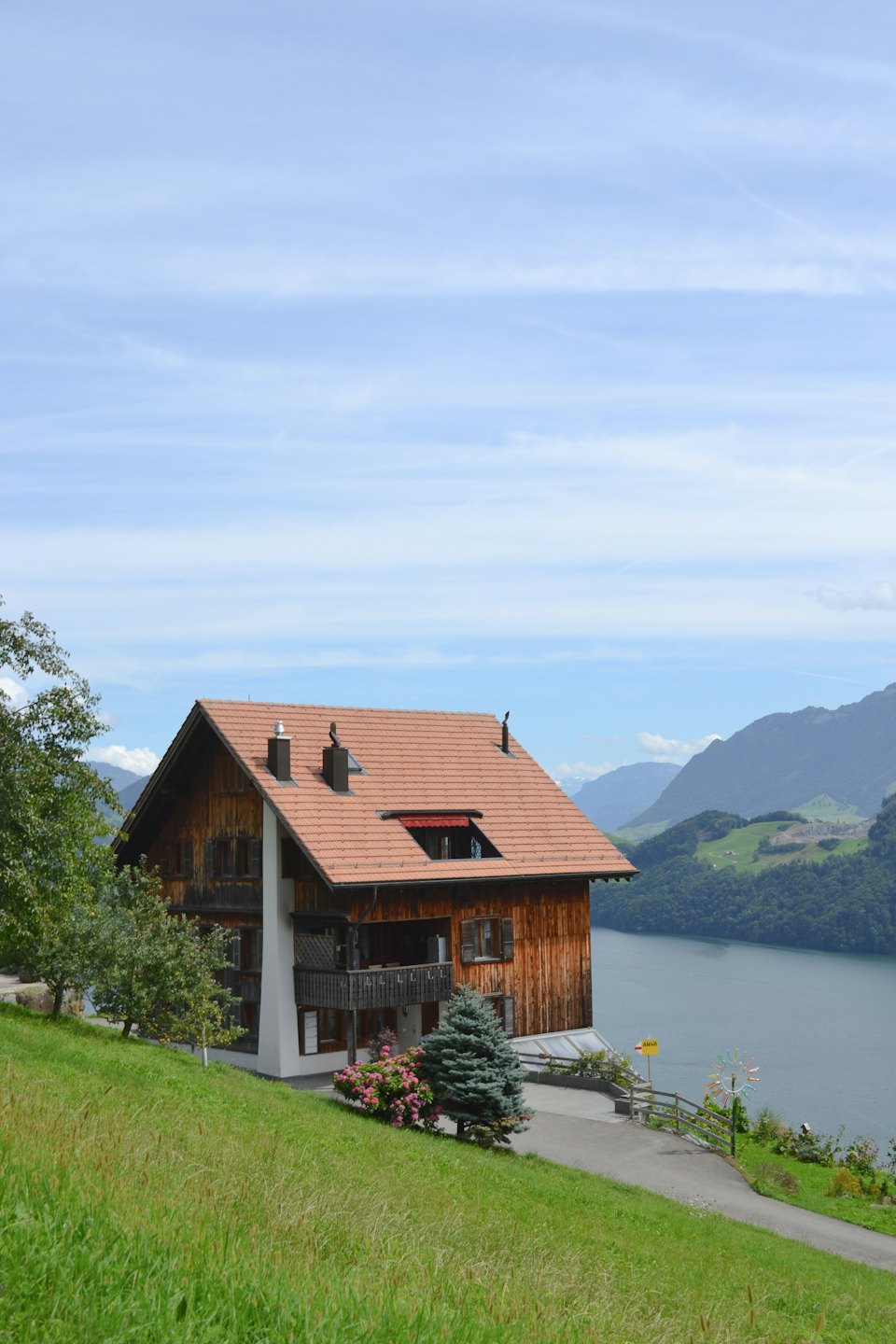 Traditionelles Holzhaus mit Blick auf einen See an einem grünen Hang.